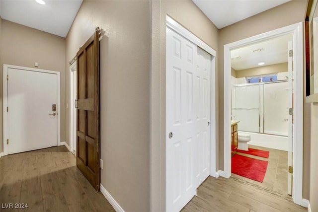 hallway with a barn door and light wood-type flooring