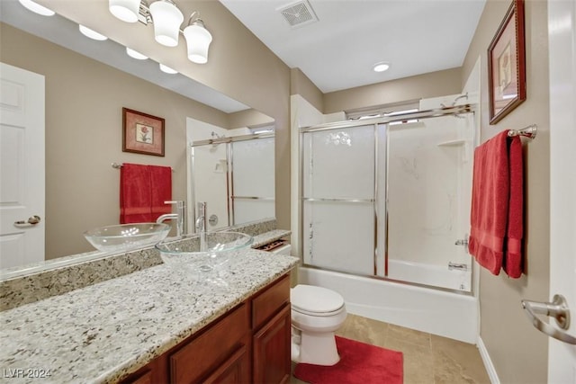 full bathroom with tile patterned flooring, enclosed tub / shower combo, vanity, and toilet