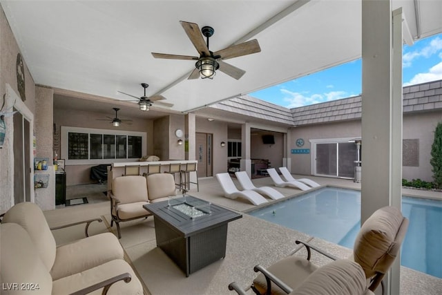 pool with ceiling fan, an outdoor living space with a fire pit, and a patio