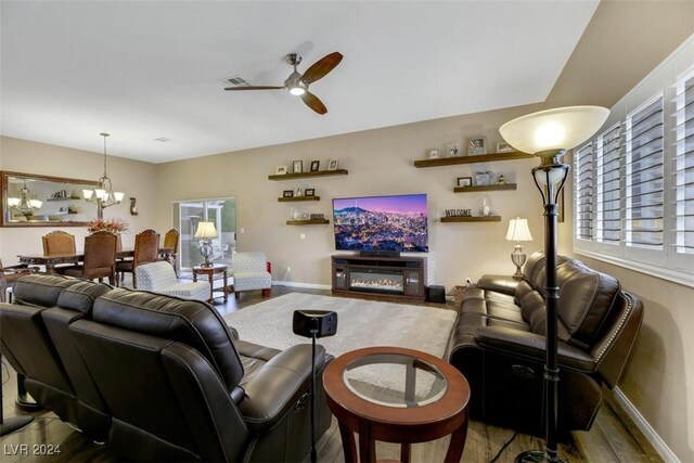 living room with hardwood / wood-style floors and ceiling fan with notable chandelier