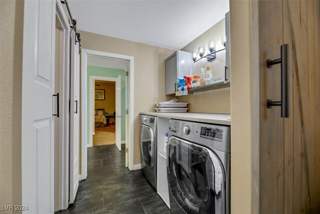 laundry area with cabinets, washing machine and dryer, and a barn door