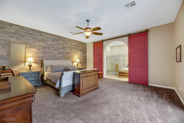 carpeted bedroom with wood walls, ceiling fan, and ensuite bathroom