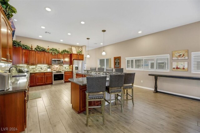 kitchen featuring a kitchen island, pendant lighting, tasteful backsplash, sink, and stainless steel appliances