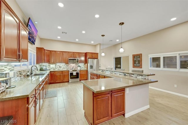 kitchen with a sink, stainless steel appliances, light stone counters, and tasteful backsplash