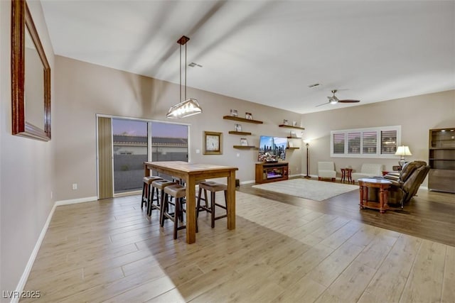 dining space featuring visible vents, baseboards, light wood finished floors, and ceiling fan