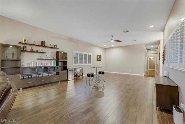 interior space with baseboards, wood finished floors, visible vents, and ceiling fan