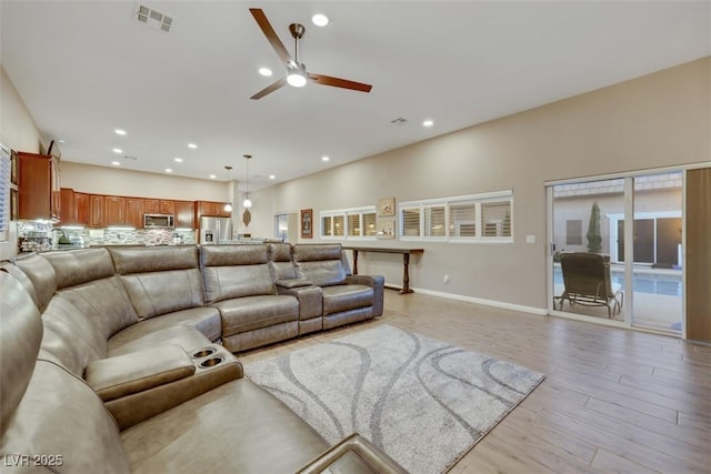 living room with recessed lighting, visible vents, baseboards, and light wood finished floors