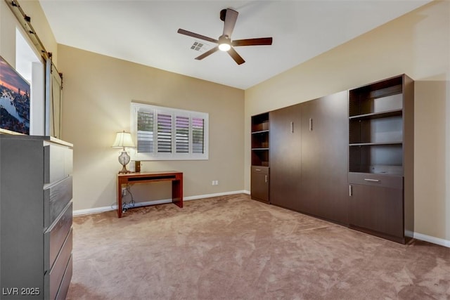 unfurnished bedroom with light colored carpet, baseboards, and a barn door