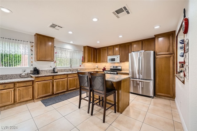 kitchen featuring a kitchen island, a kitchen bar, a healthy amount of sunlight, and stainless steel appliances