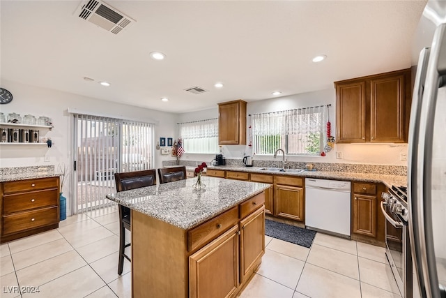 kitchen featuring sink, high end stainless steel range, dishwasher, a kitchen island, and a breakfast bar area