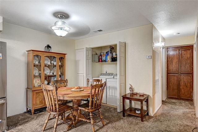 carpeted dining area with a textured ceiling and washing machine and clothes dryer