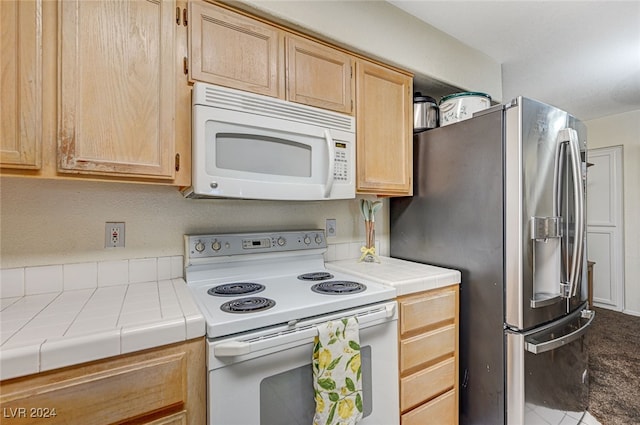 kitchen with tile countertops, light brown cabinetry, and white appliances