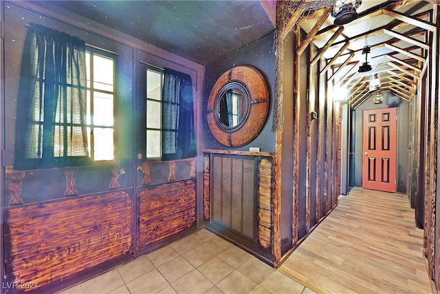 corridor with light hardwood / wood-style floors and vaulted ceiling