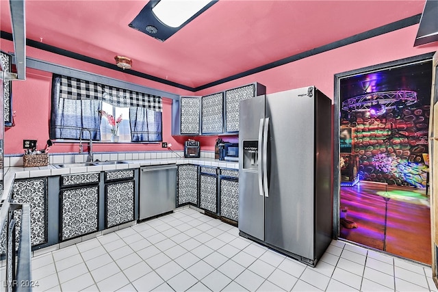 kitchen with tile countertops, sink, light tile patterned floors, and appliances with stainless steel finishes