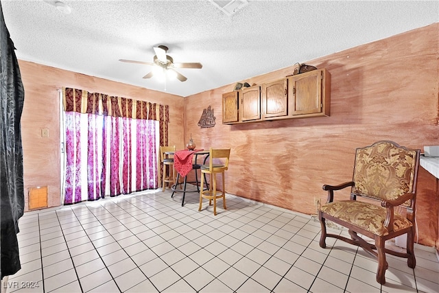 sitting room featuring ceiling fan, light tile patterned flooring, and a textured ceiling