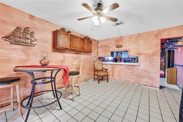 interior space featuring ceiling fan, light tile patterned floors, and a textured ceiling