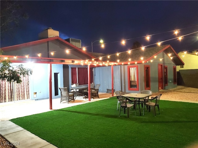 back house at twilight with a patio area and a yard