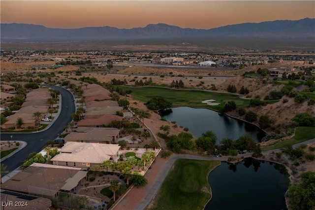 aerial view at dusk featuring a water and mountain view