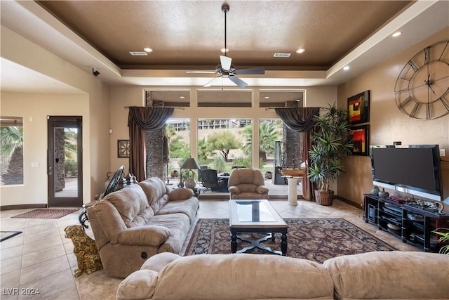 tiled living room featuring a tray ceiling and ceiling fan