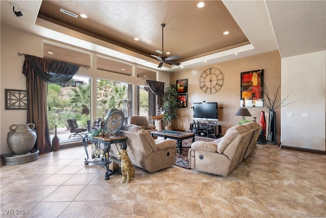 living room with ceiling fan and a raised ceiling