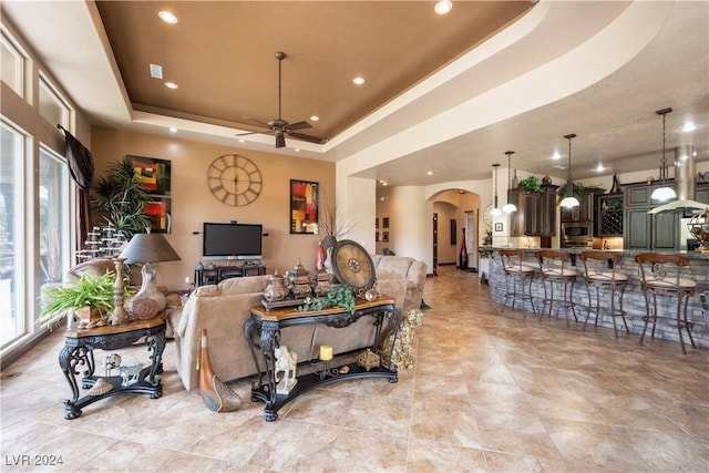 living room featuring a raised ceiling and ceiling fan