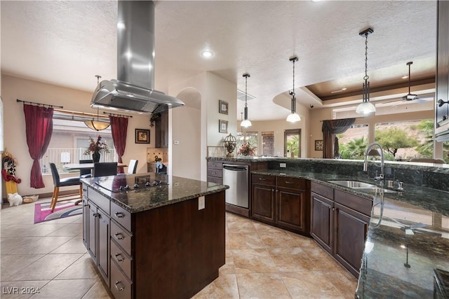 kitchen with sink, hanging light fixtures, dark stone countertops, a raised ceiling, and island exhaust hood