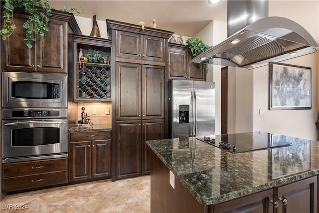 kitchen with dark stone countertops, stainless steel appliances, island exhaust hood, dark brown cabinetry, and a kitchen island