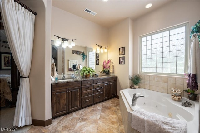 bathroom with vanity, a relaxing tiled tub, and a healthy amount of sunlight