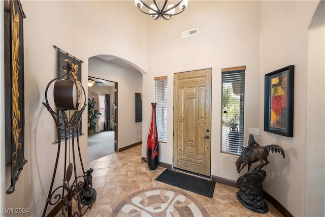 foyer entrance with an inviting chandelier, light tile patterned floors, and a high ceiling