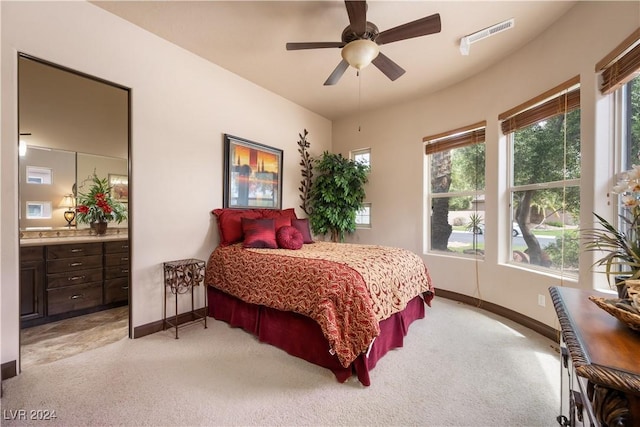 carpeted bedroom featuring multiple windows, ceiling fan, and ensuite bath