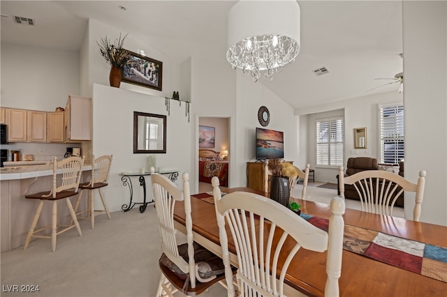 carpeted dining area featuring ceiling fan with notable chandelier and high vaulted ceiling