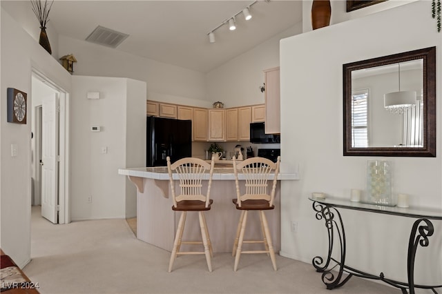 kitchen featuring a breakfast bar area, light carpet, black appliances, and lofted ceiling