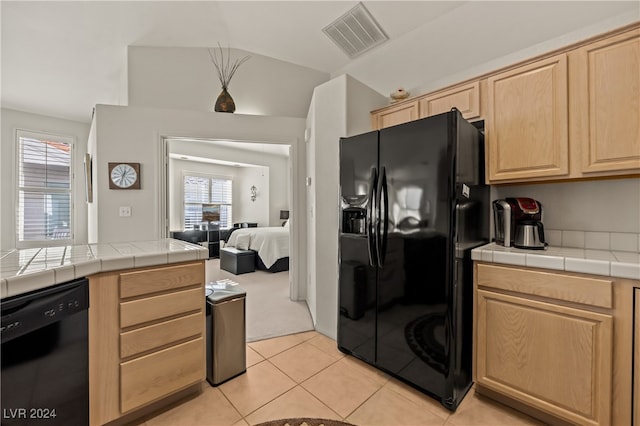 kitchen featuring light brown cabinets, lofted ceiling, black appliances, tile counters, and light tile patterned flooring