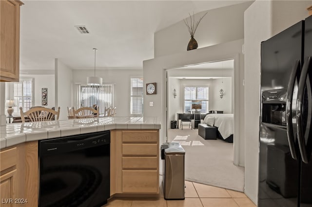 kitchen featuring washer / dryer, tile countertops, light colored carpet, and black appliances