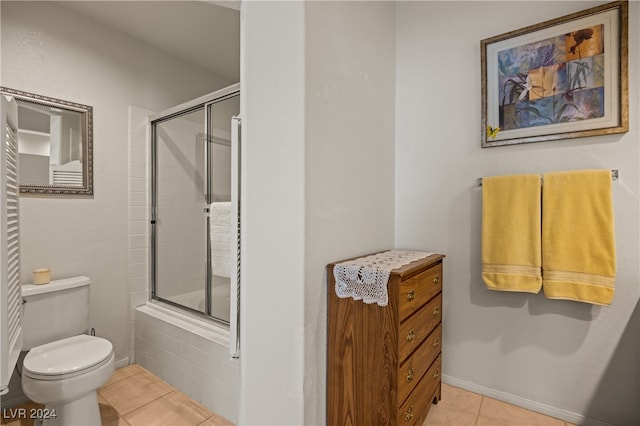 bathroom with tile patterned flooring, combined bath / shower with glass door, and toilet