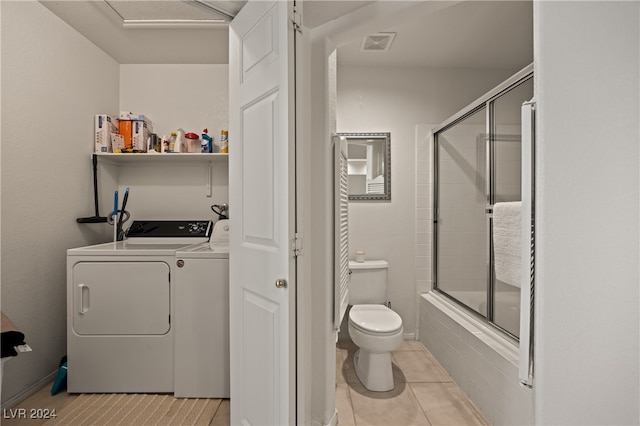 bathroom featuring tile patterned floors, separate washer and dryer, combined bath / shower with glass door, and toilet