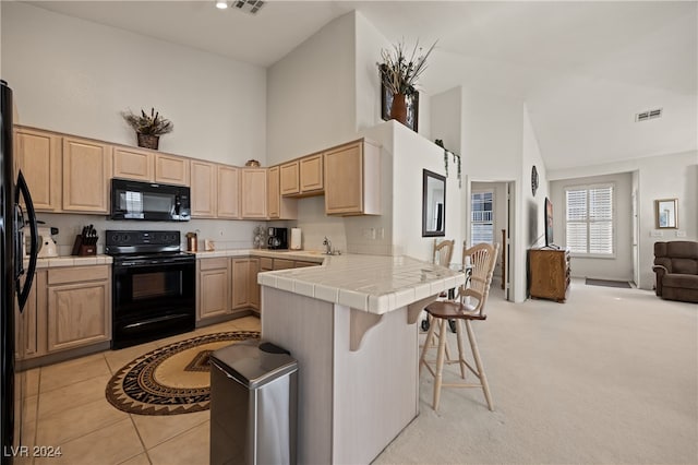 kitchen with black appliances, tile counters, light carpet, and high vaulted ceiling