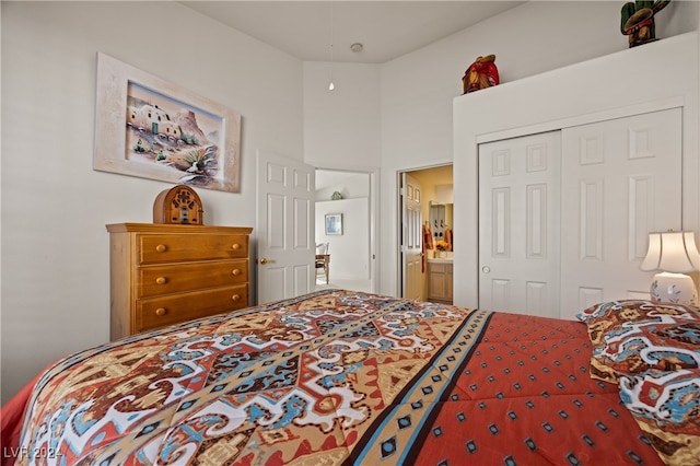 bedroom with ensuite bathroom, a towering ceiling, and a closet