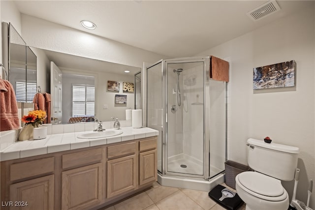 bathroom featuring tile patterned floors, vanity, toilet, and an enclosed shower