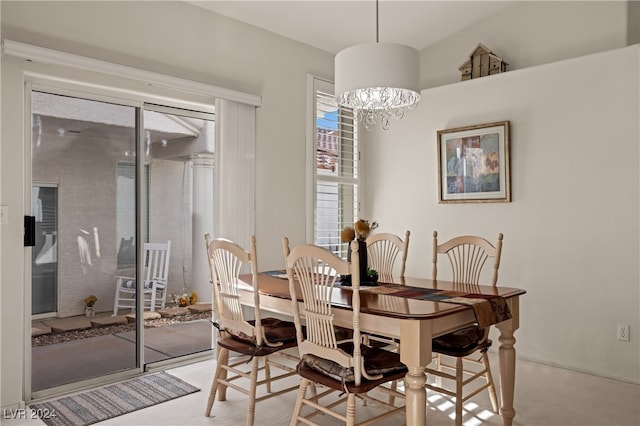 dining space with lofted ceiling, light carpet, and an inviting chandelier