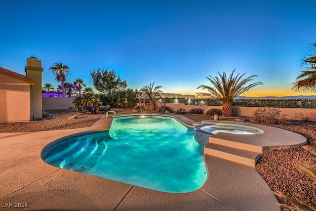 pool at dusk featuring an in ground hot tub