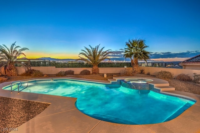 pool at dusk featuring an in ground hot tub