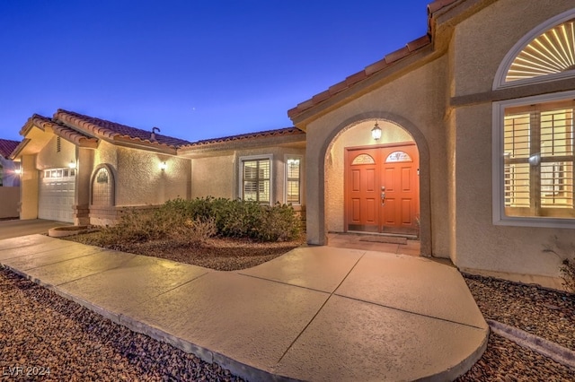 exterior entry at dusk featuring a garage