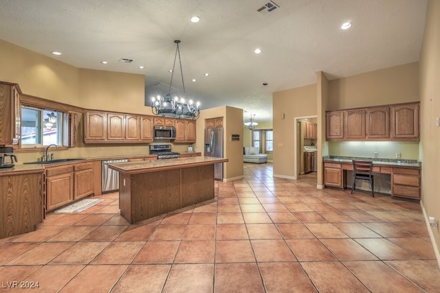 kitchen featuring light tile patterned floors, appliances with stainless steel finishes, high vaulted ceiling, a kitchen island, and a chandelier