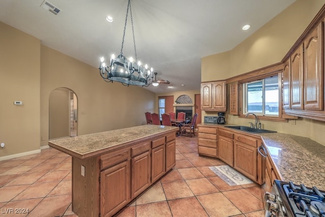 kitchen featuring a center island, sink, light tile patterned floors, and stainless steel range oven