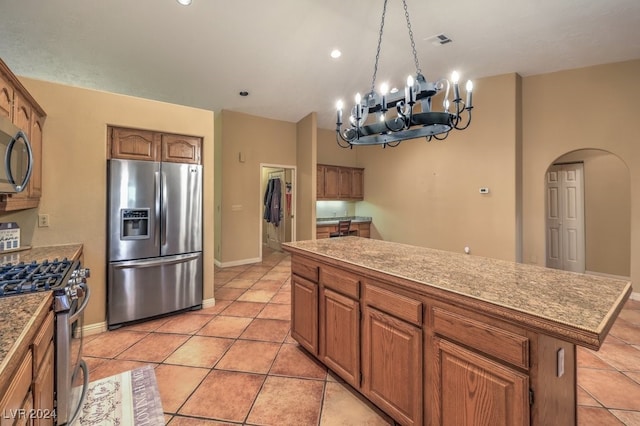 kitchen featuring stainless steel appliances, a center island, light tile patterned floors, and a notable chandelier