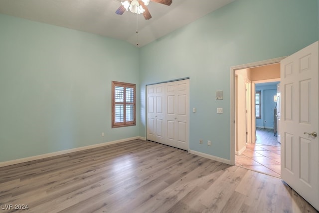 unfurnished bedroom with multiple windows, light hardwood / wood-style floors, a closet, and ceiling fan