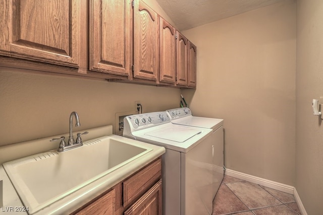 laundry area with sink, light tile patterned floors, washing machine and dryer, cabinets, and a textured ceiling