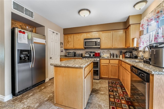 kitchen with light stone counters, a kitchen island, sink, and stainless steel appliances