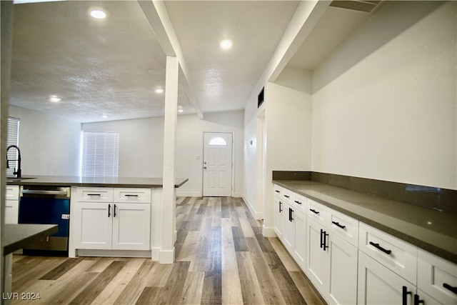 kitchen featuring dishwasher, white cabinets, sink, light wood-type flooring, and a textured ceiling